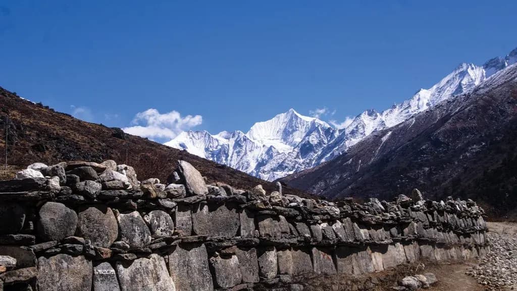 Stone mani wall below snow‑clad Langtang peaks