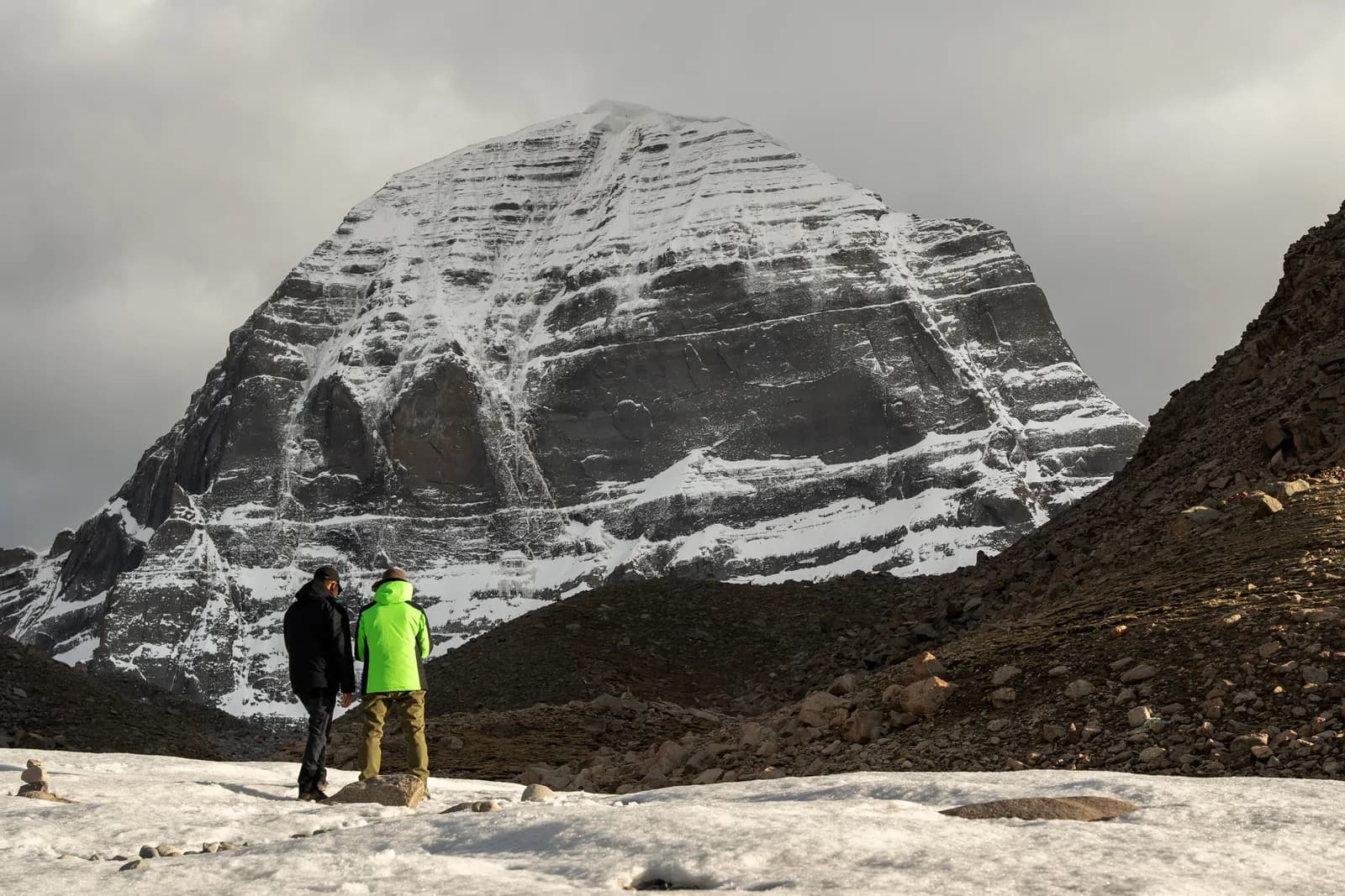 Two pilgrims on the snow below Mount Kailash's north face