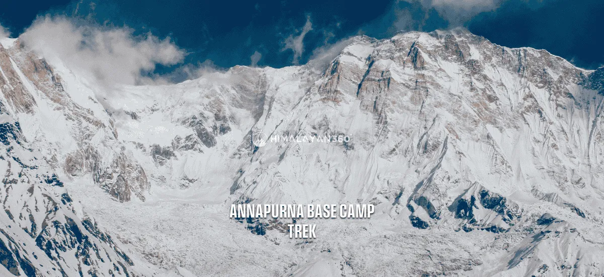 Snow capped Annapurna range with partial cloudy sky and a close-up view of peak mountains and glacier, text overlay saying "Annapurna Base Camp Trek" by Himalayan 360.