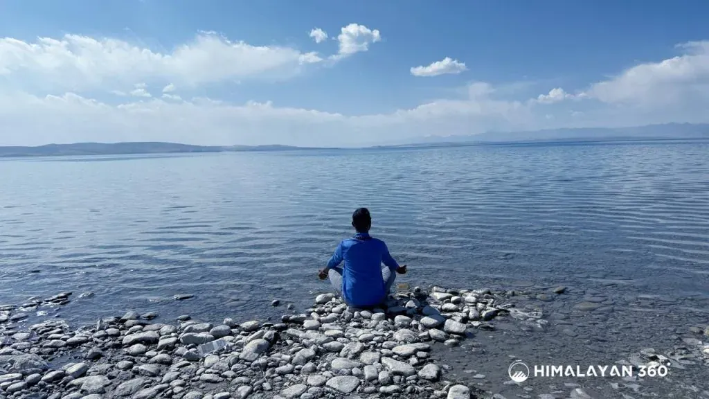 A man in a meditating pose in Rocky Mansarovar Lake