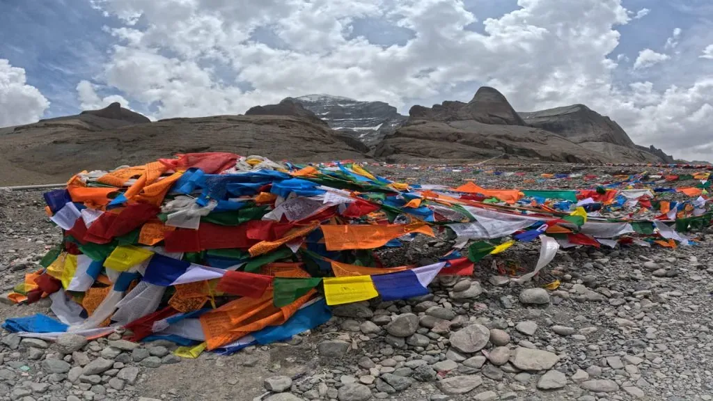 prayer flags fluttering on rocky ground below mount kailash